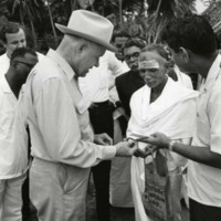 Photograph of Congressman Poage presenting Kennedy half-dollar to Hindu holy man<br /><br />
