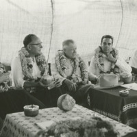 Photograph of the Congressional Delegation inside a tent wearing garlands<br /><br />
